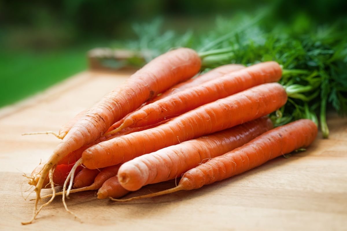 A bunch of fresh carrots on a wooden table